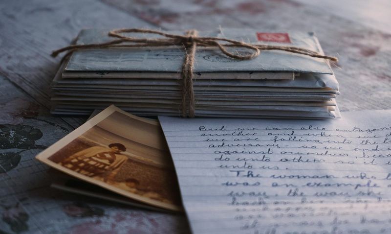 A bundle of old letters tied with string beside a handwritten page