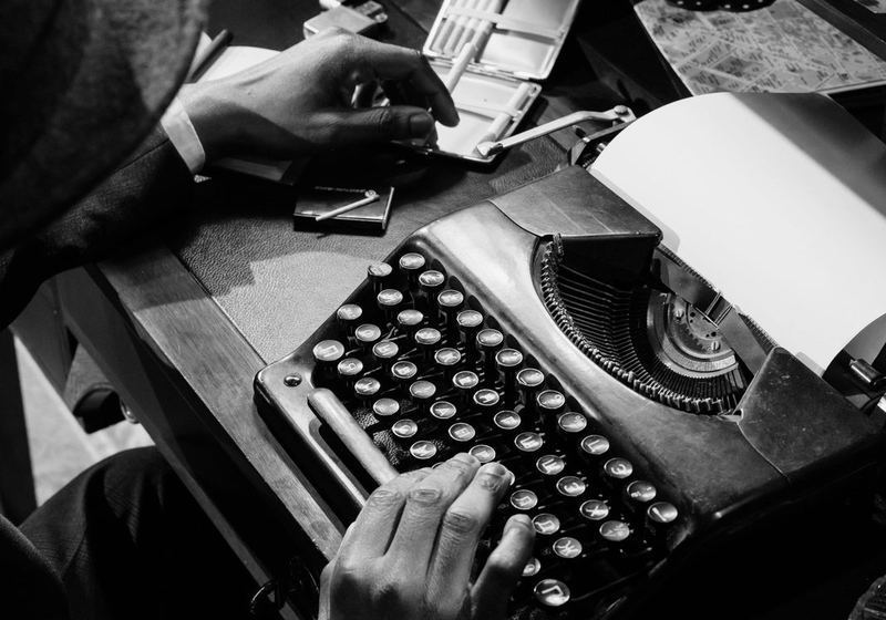 An older man typing on a vintage typewriter